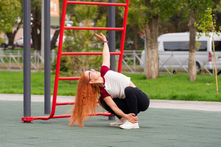 Woman stretching upward while squatting during outdoor exercise in a park.