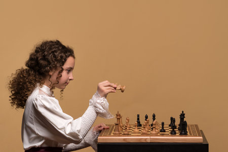 Young girl chess player focused on moving a chess piece during gameplay.の写真素材