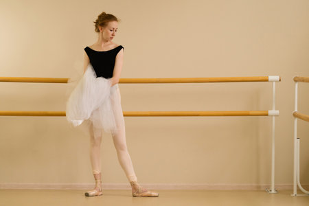 A ballet dancer gracefully poses in a dance studio, showcasing elegance.の写真素材
