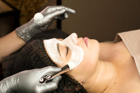 A facial treatment applying a white cream mask using a brush, enhancing skin care.の写真素材