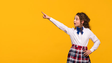 Girl pointing to the side, surprised expression, plaid skirt.の写真素材