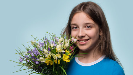 A young girl smiling and holding a colorful bouquet of flowers, enjoying a cheerful moment.の写真素材