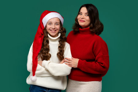 Mum and teenage daughter pose in holiday sweaters, smiling happilyの写真素材