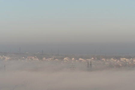 A foggy morning view of a town with houses and power lines.