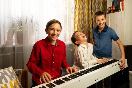 Smiling boys enjoying music while playing the piano together. Practicing piano at home. Education,...