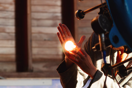 Man's hand illuminated by bright telescope light reflection. The projection of the solar disk on the...