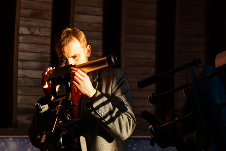 Focused man looks through solar telescope in observatory.の写真素材