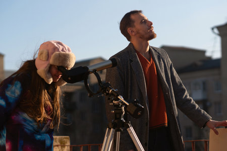 Instructor looks upward while student peers into solar telescope. Education, teaching, learning conceptの写真素材