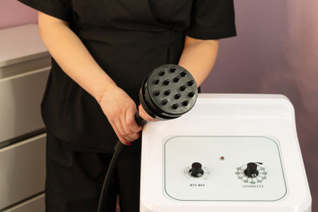 Therapist presenting cavitation handpiece above aesthetic control panel. Keywords: Hardware cosmetology, beauty and health.の写真素材