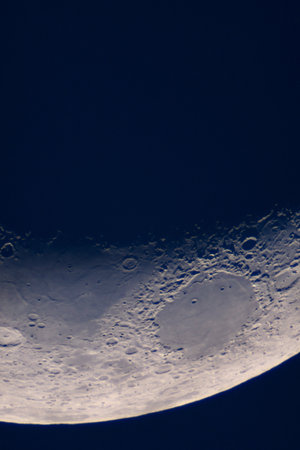 Crescent Moon features large crater floor and shadowed rim. Moon's terminator line, showcasing sharply defined craters, rugged mountain ranges and smooth lunar maria under low-angle sunlight.の写真素材