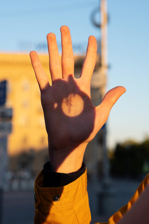 Vertical close-up of hand with plant shadow pattern outdoors. Observations of the sun. Projection image of Sunの写真素材