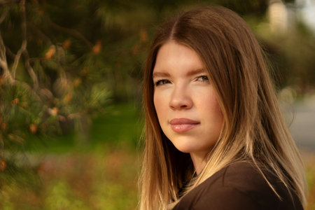 Close-up portrait of young woman outdoors under natural sunlight.