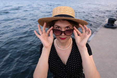Portrait of woman adjusting sunglasses while facing the camera.の写真素材
