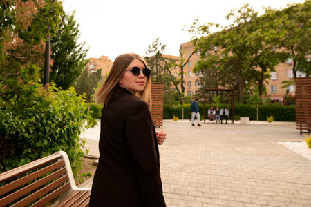 Stylish young woman walking outdoors in urban park daytime.の写真素材