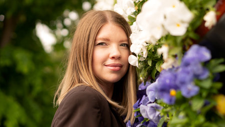 Young woman posing near outdoor floral wall looking forward.の写真素材