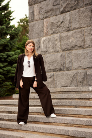 Young woman confidently standing on stone staircase, outdoors portrait.の写真素材