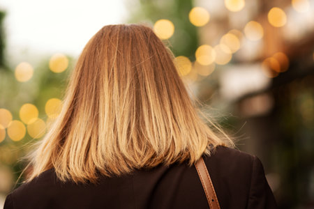 Back view of blonde woman with shoulder-length hair outdoors.