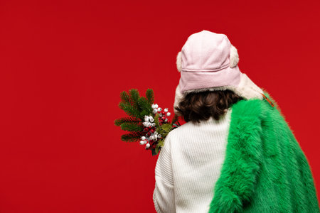 Woman in a pink winter hat and green coat holding a festive bouquet.