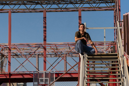 Close-up of person holding steady crouch position on stair railing in steel-framed urban environment, emphasizing body control and composure.の写真素材