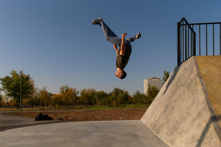 Male freerunner captured upside down mid-backflip off a concrete wall during parkour training in an...