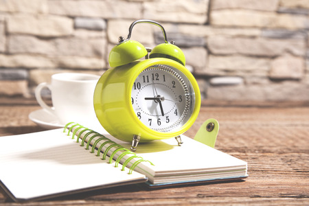 clock on notepad and coffee on deskの写真素材