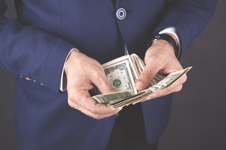 young business man hand holding money on dark background