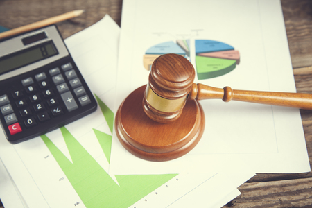 wooden gavel and calculator on graph on tableの写真素材