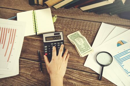 woman hand notepad and calculator with money on tableの写真素材