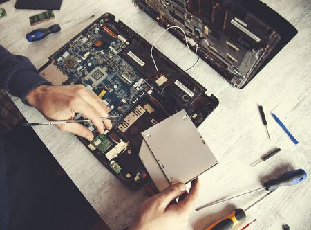 Man hand laptop disassembling in tool on tableの写真素材