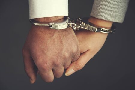 woman  and man hand handcuffs on dark backgroundの写真素材