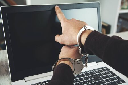 young man hand handcuffs on computer cameraの写真素材