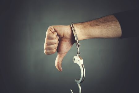 young  man hand handcuffs on dark backgroundの写真素材