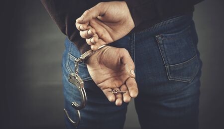 young man hand open handcuffs on dark backgroundの写真素材