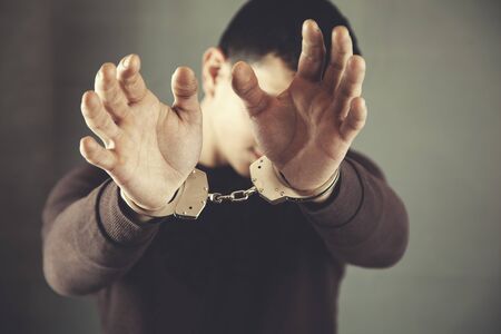 young man hand handcuffs stop sign on dark backgroundの写真素材
