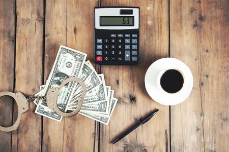 handcuffs on money and calculator on tableの写真素材