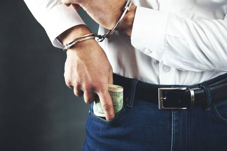 man hand money with handcuffs in pocketの写真素材