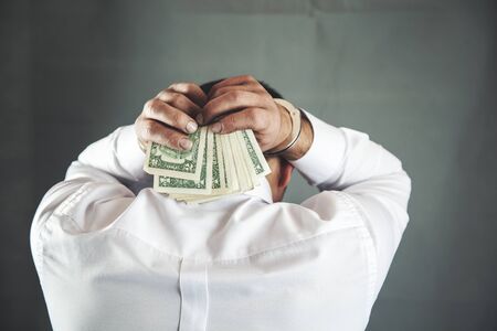 sad man hand money with handcuffs on dark backgroundの写真素材