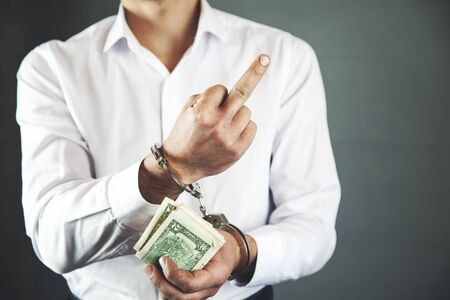 man hand handcuffs with  money and middle fingerの写真素材