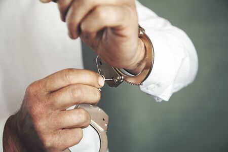 man hand handcuffs and key on dark background