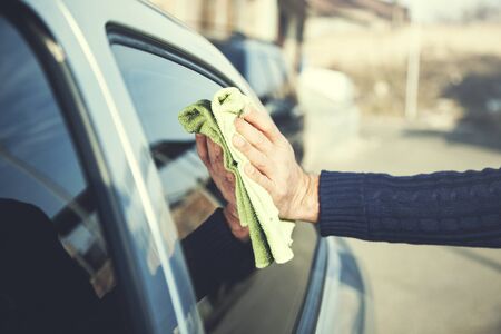 young man washing a car with a ragの写真素材