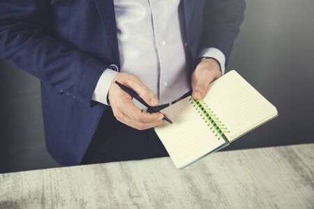 man hand notepad on wooden table backgroundの写真素材