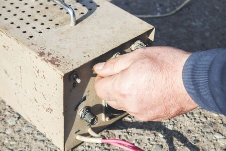 man hand holding car battery charger in asphalt