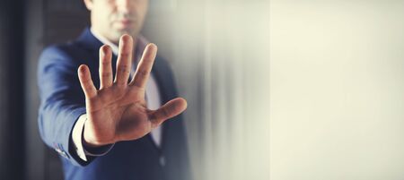 young business man hand stop sign  on dark backgroundの写真素材
