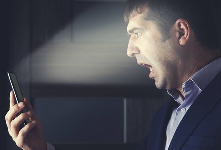 angry man hand phone on dark background