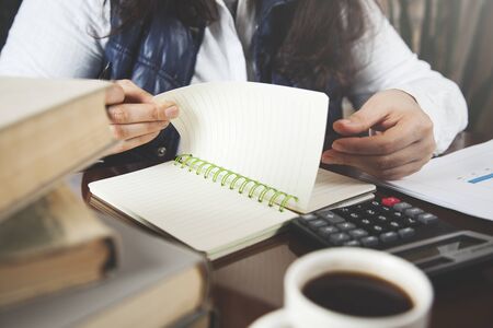 woman hand notepad with calculator on desk