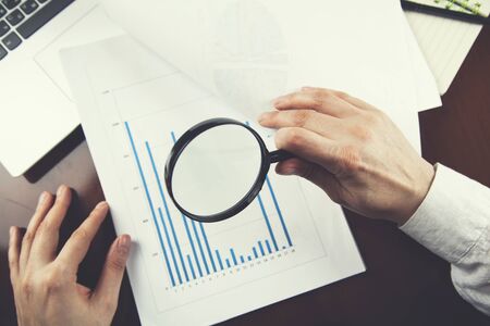 woman hand magnifier with graph on keyboard