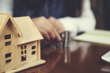 woman hand coins with house model on deskの写真素材