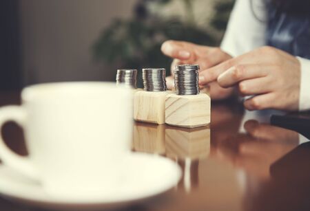 woman hand coins on wooden cubes on tableの写真素材