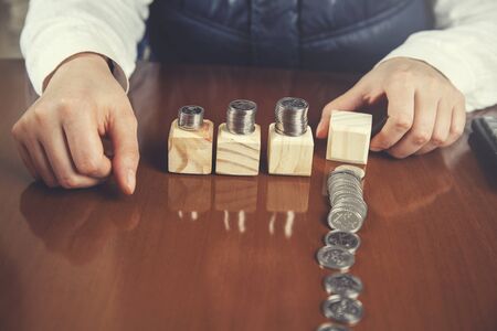 woman hand coins on wooden cubes on tableの写真素材