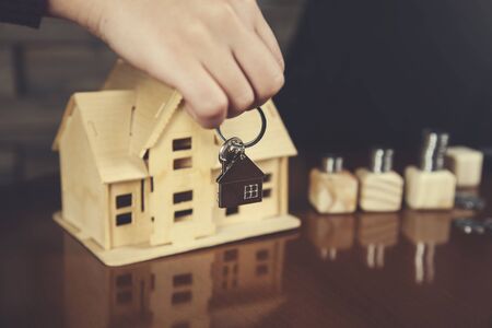 womans hand key with house model on deskの写真素材